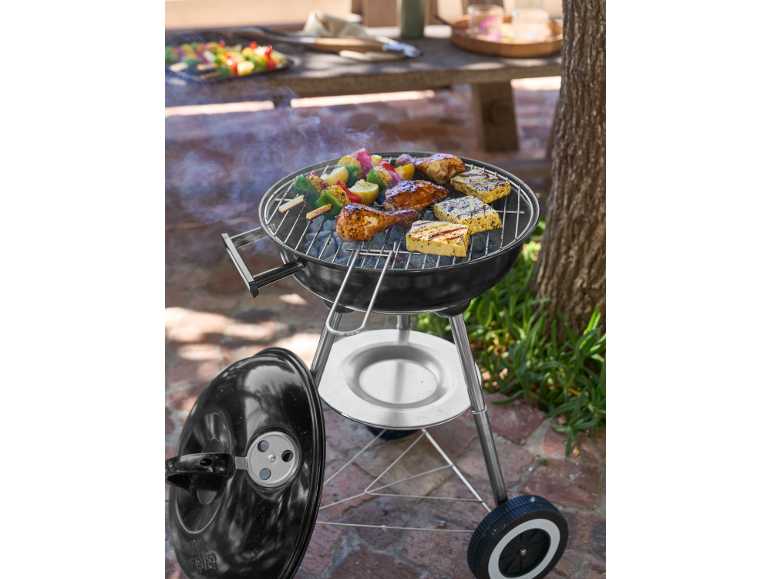 Barbecue au charbon avec poulet, halloumi et brochettes de légumes cuisant en extérieur.
