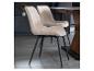 Deux chaises de salle à manger en velours côtelé beige avec pieds noirs à côté d'une table en bois.