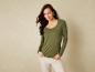 Une femme portant un t-shirt vert à manches longues et un pantalon blanc.