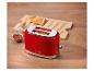 Grille-pain rouge avec deux toasts, de la confiture et un couteau à tartiner sur une table en bois.
