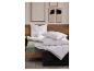 Un lit avec un drap-housse vert clair, des oreillers blancs et une couette matelassée blanche, avec de l'art encadré au mur.