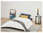 Couette blanche, oreillers et table de chevet dans une chambre minimaliste.
