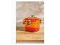 Trois cocottes Le Creuset orange empilées sur une table en bois.