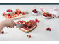 Gâteau en forme de cœur aux fruits, en train d'être coupé, entouré de fraises, framboises et cerises.