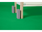 Gros plan d'un pied de meuble en bois clair avec un pied en plastique gris sur fond vert.