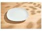 Assiette blanche vide sur une table en bois avec des ombres de feuilles