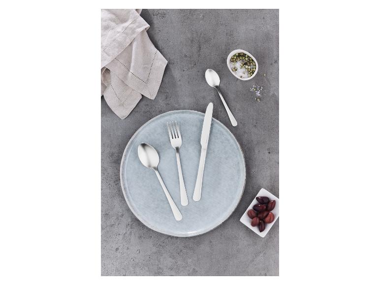 Une fourchette, un couteau et une cuillère sur une assiette grise avec un bol d'olives.