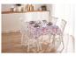 Une table avec une nappe fleurie et des chaises blanches dans une salle à manger lumineuse.