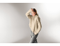 Femme portant un pull à col roulé beige et un pantalon gris.