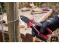 Personne gantée coupant du fil avec une pince près d'un poteau en bois.