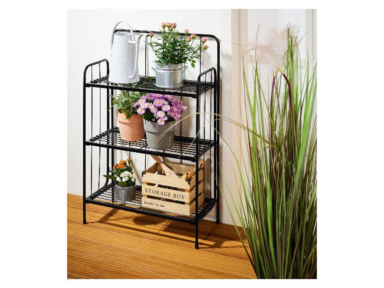 Étagère métallique noire avec plantes en pot et une boîte de rangement en bois.
