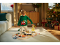 Enfant en pull de Noël jouant avec un train en bois et des jouets de construction.