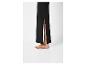 Robe longue noire fendue et sandales plates couleur moutarde.