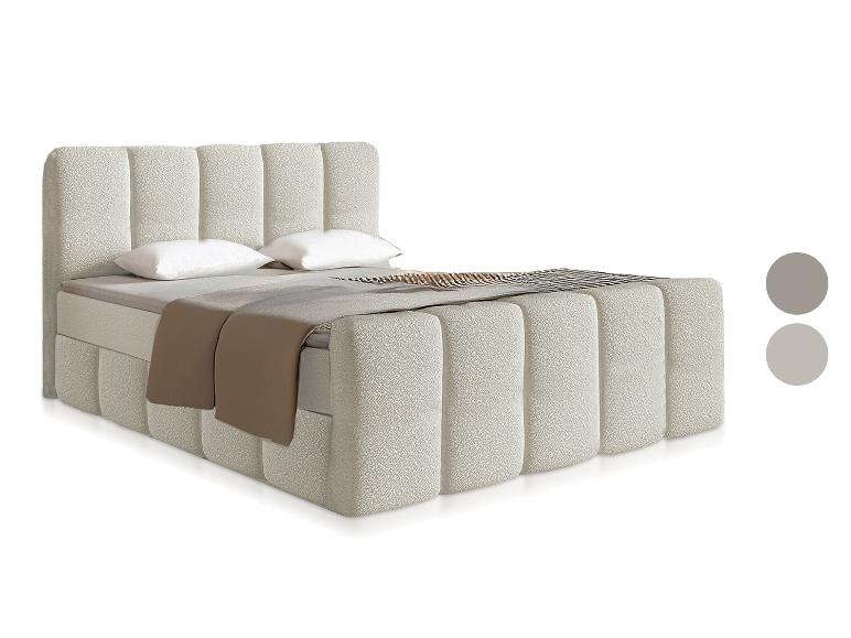 Lit double rembourré beige avec tête et pied de lit capitonnés, oreillers blancs et couverture marron.