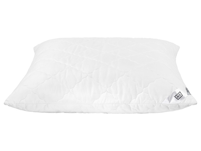 Un oreiller blanc matelassé avec une étiquette indiquant 95 °C.