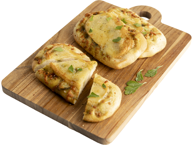 Focaccia au pesto et fromage sur une planche en bois, coupée en morceaux.