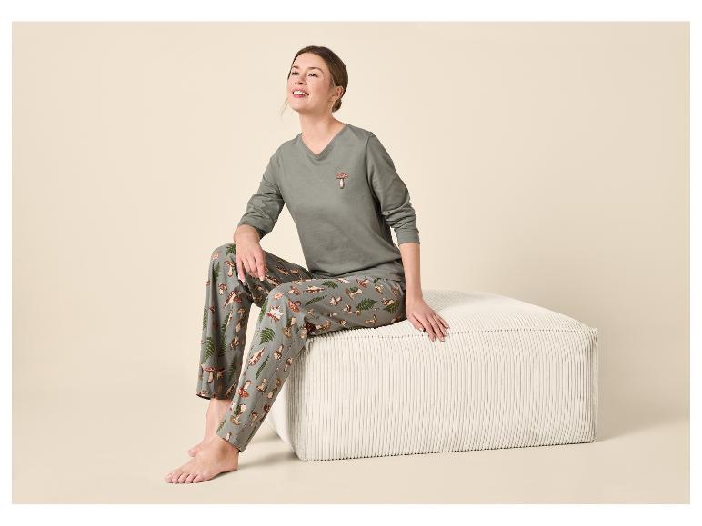 Femme en pyjama imprimé champignons assise sur un pouf blanc, regardant vers le haut et souriant.