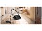 Aspirateur traîneau noir nettoyant un tapis dans une buanderie moderne.