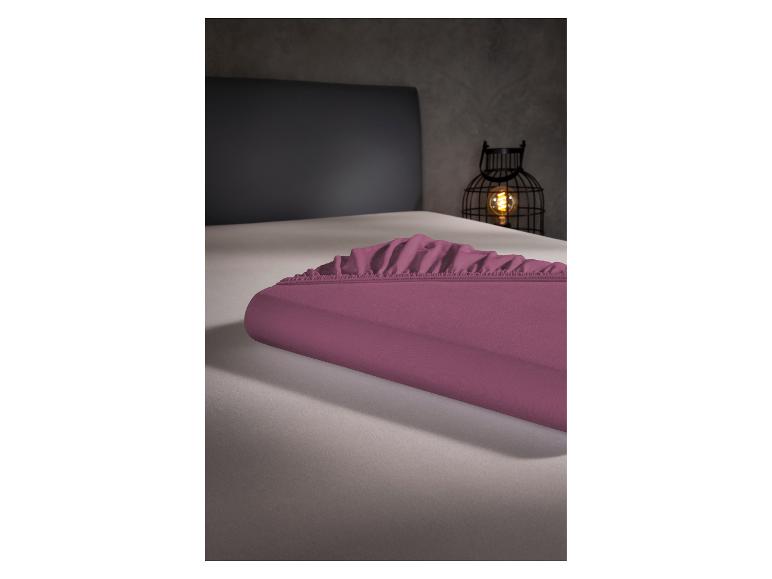 Drap-housse violet sur un lit, avec une lanterne décorative en arrière-plan.