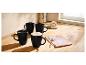 Trois mugs noirs et un gâteau roulé sur une table en bois.