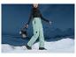 Une femme avec un casque et un pantalon de ski Mountain Warehouse dans la neige.