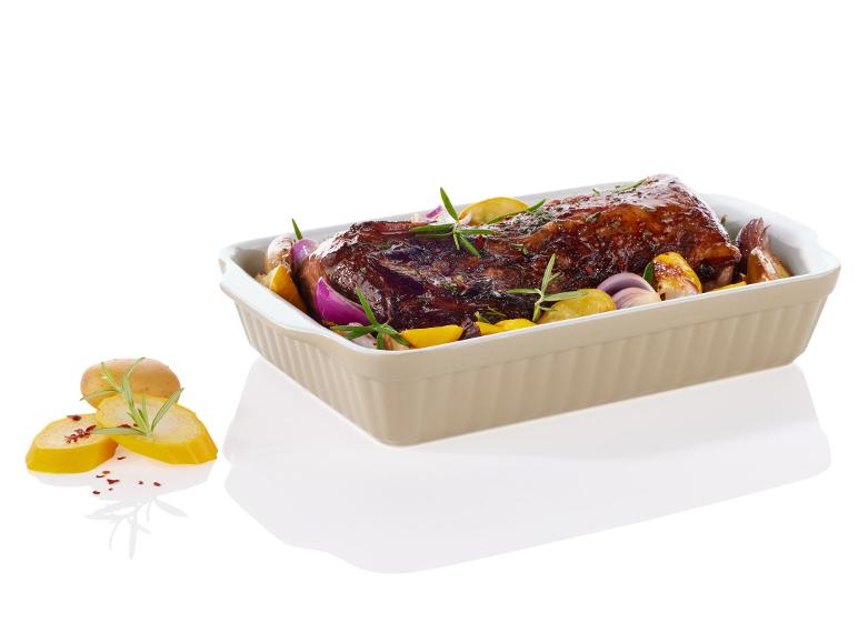 Viande rôtie avec des pommes de terre, des oignons et du romarin dans un plat allant au four.