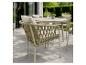 Ensemble de jardin avec table ronde et chaises à dossier tressé sur une terrasse.
