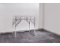 Table pliante avec plateau gris et cadre métallique dans une pièce vide.
