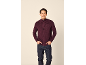 Homme portant un gilet bordeaux zippé et un jean bleu foncé.