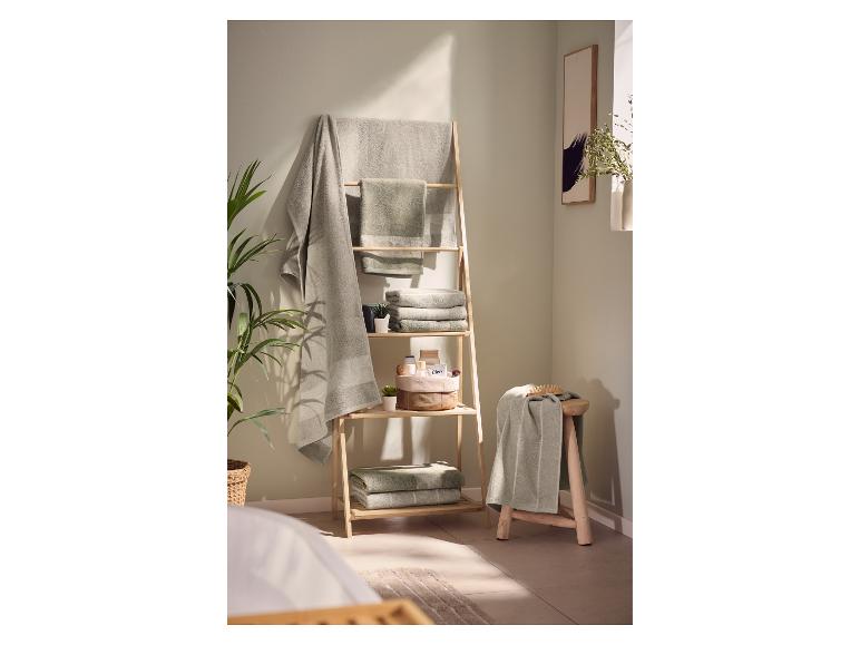 Intérieur de salle de bain avec étagère échelle en bois et serviettes vertes.