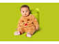 Bébé dans une combinaison de renne marron duveteuse assis sur fond vert.