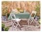 Table et chaises pliantes blanches, nappe verte, ambiance jardin.