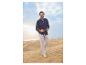 Homme en chemise bleue et pantalon beige marchant dans les dunes de sable.