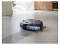 Robot aspirateur nettoyant une tache de sauce sur le sol d'une cuisine.
