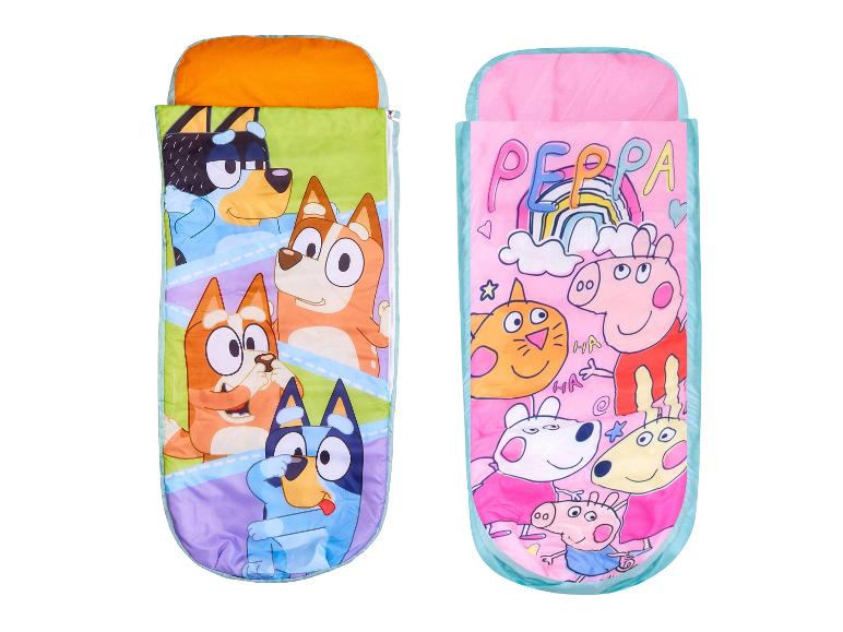 Deux sacs de couchage pour enfants, l'un avec des chiens de dessin animé et l'autre avec des cochons de dessin animé.