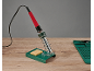 Fer à souder avec support et éponge, et tapis en silicone sur une table en bois.
