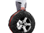 Personne portant une roue de voiture dans un sac de protection noir avec une sangle rouge.