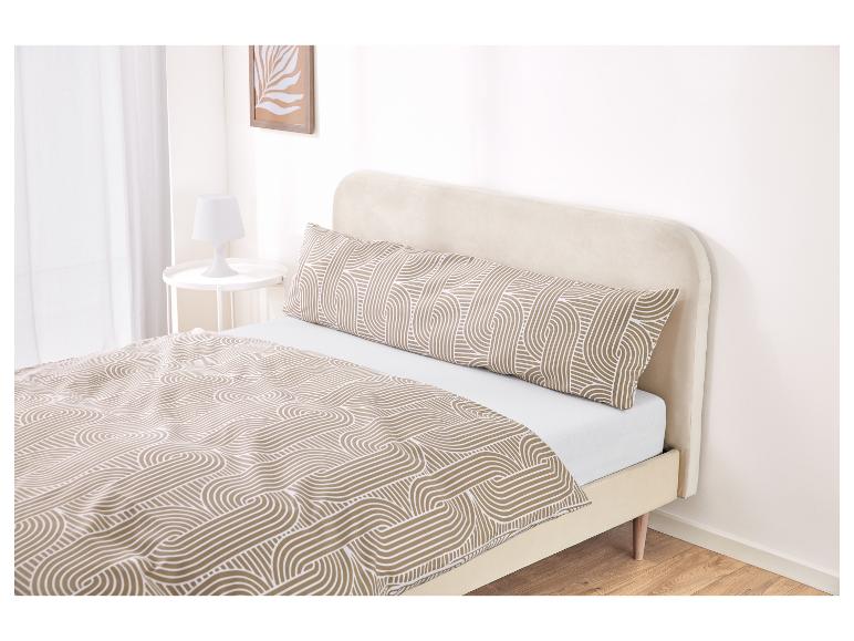 Un lit avec une tête de lit beige et une couette et un oreiller de corps à motifs.