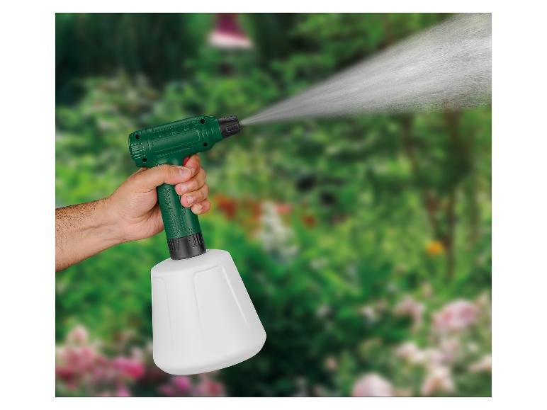 Pulvérisateur de jardin manuel avec de l'eau pulvérisée, tenu par une personne sur fond vert.