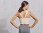Une femme porte un soutien-gorge de sport blanc et un legging gris.