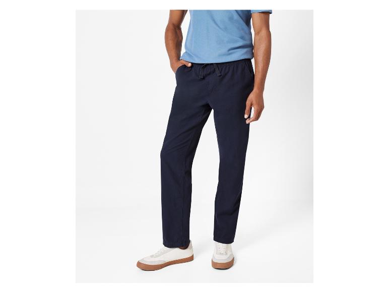 Un homme portant un pantalon bleu marine et des baskets blanches.