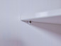 Une étagère en bois blanche fixée à un mur avec une vis.