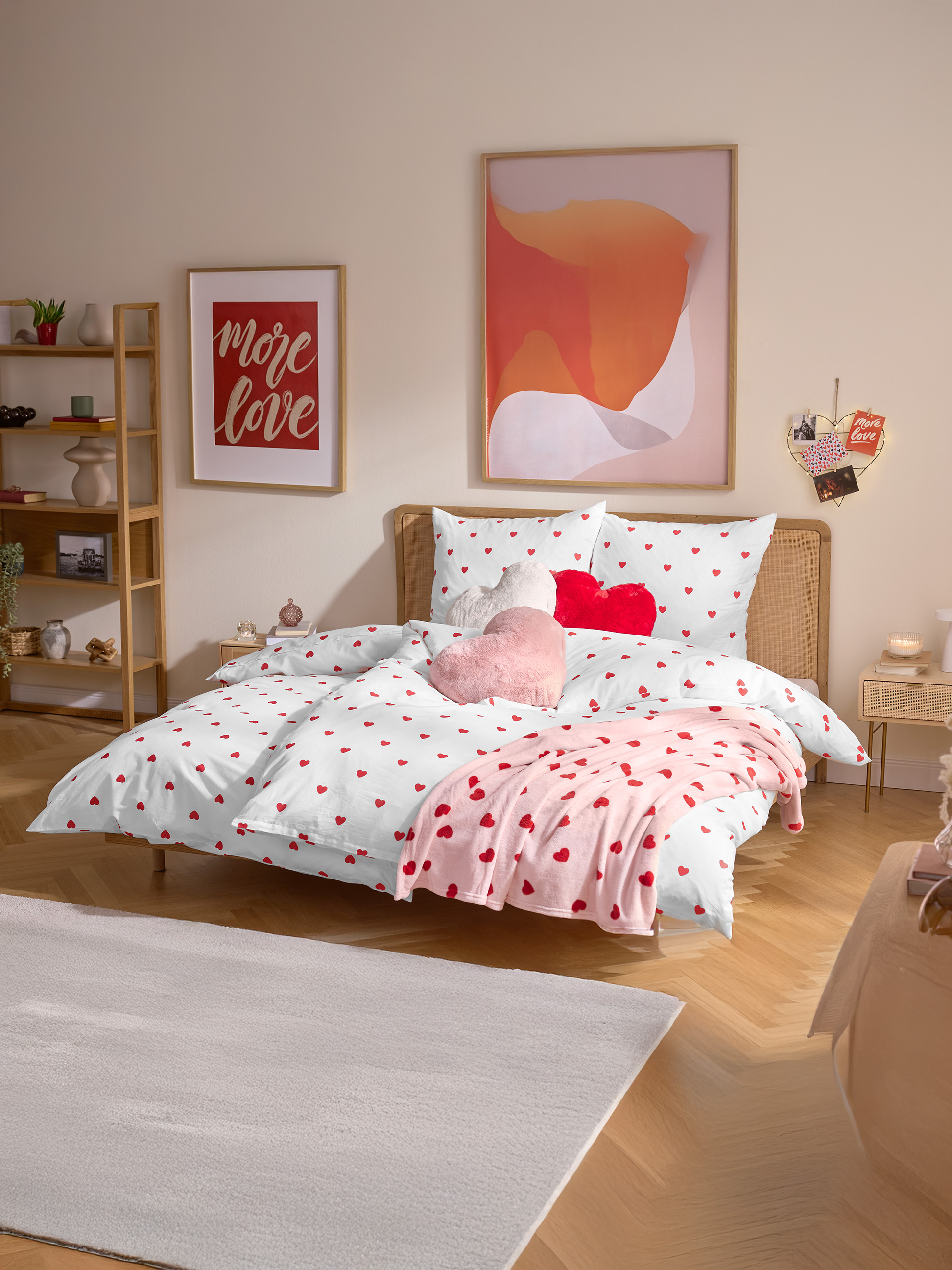 Chambre avec parure de lit à cœurs, couverture rose et coussins en forme de cœur.