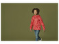 Une fille porte une veste rouge à imprimé floral et un jean bleu.