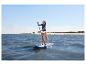Une femme fait du stand up paddle sur l'eau avec la planche bleue HOME DELUXE Moana.