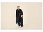 Femme en trench-coat noir, jean large et baskets blanches.