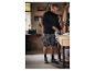 Un homme travaille dans son atelier, portant un sweat-shirt, un short et des chaussures de sécurité Parkside.