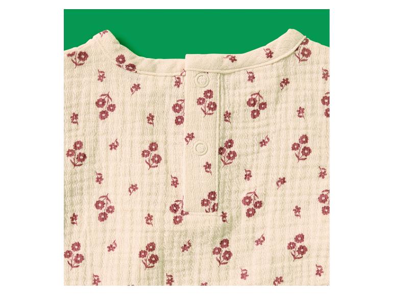 Vêtement bébé beige à imprimé floral rouge-brun et boutons au niveau du col.