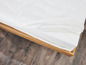 Un matelas blanc avec un cadre en bois sur un sol en bois.
