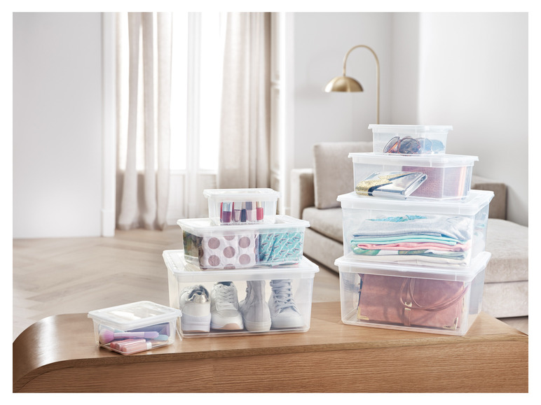 Boîtes de rangement transparentes contenant des vêtements, des chaussures et du maquillage.